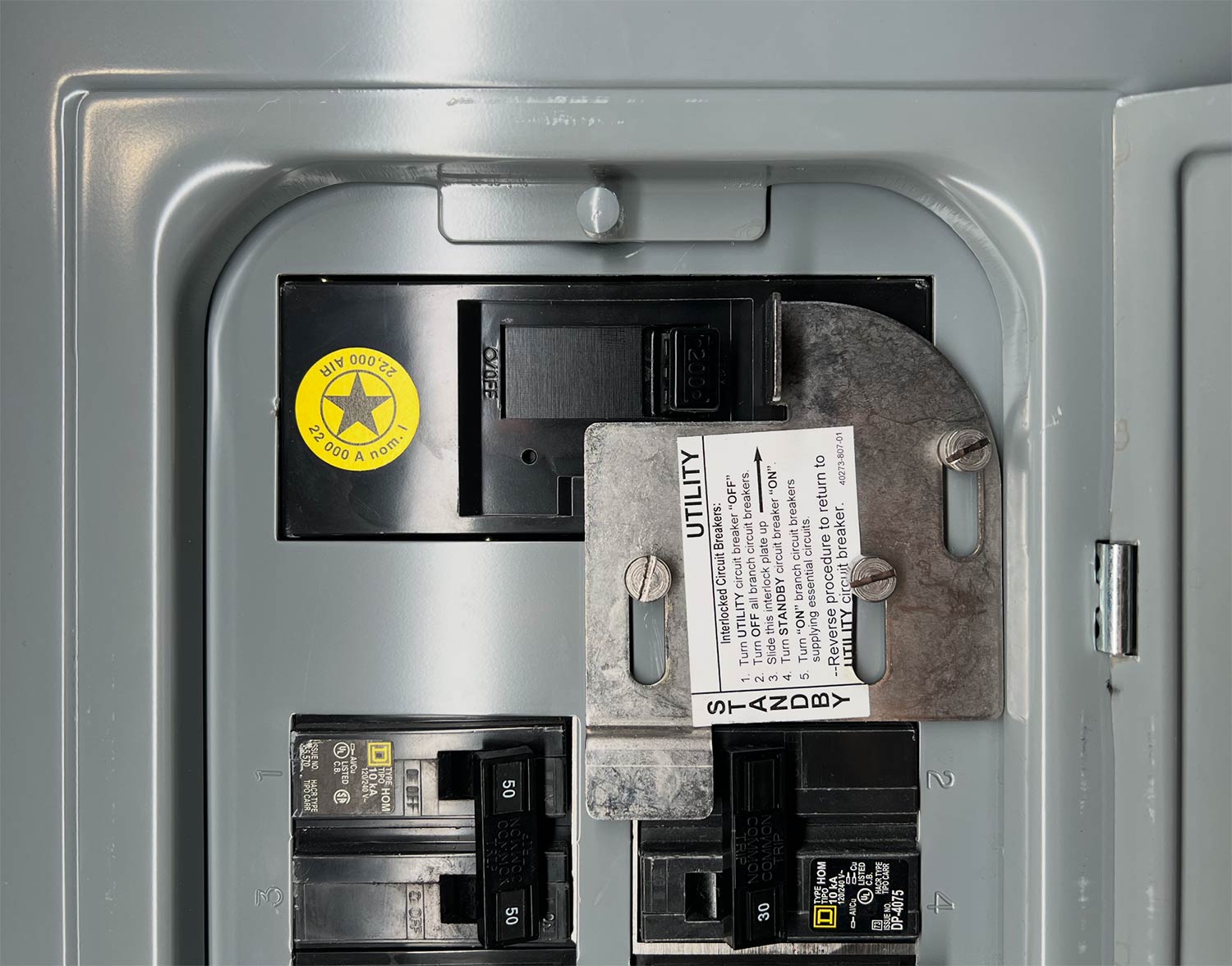 Generator interlock plate installed over the main and standby breakers in a residential electrical panel