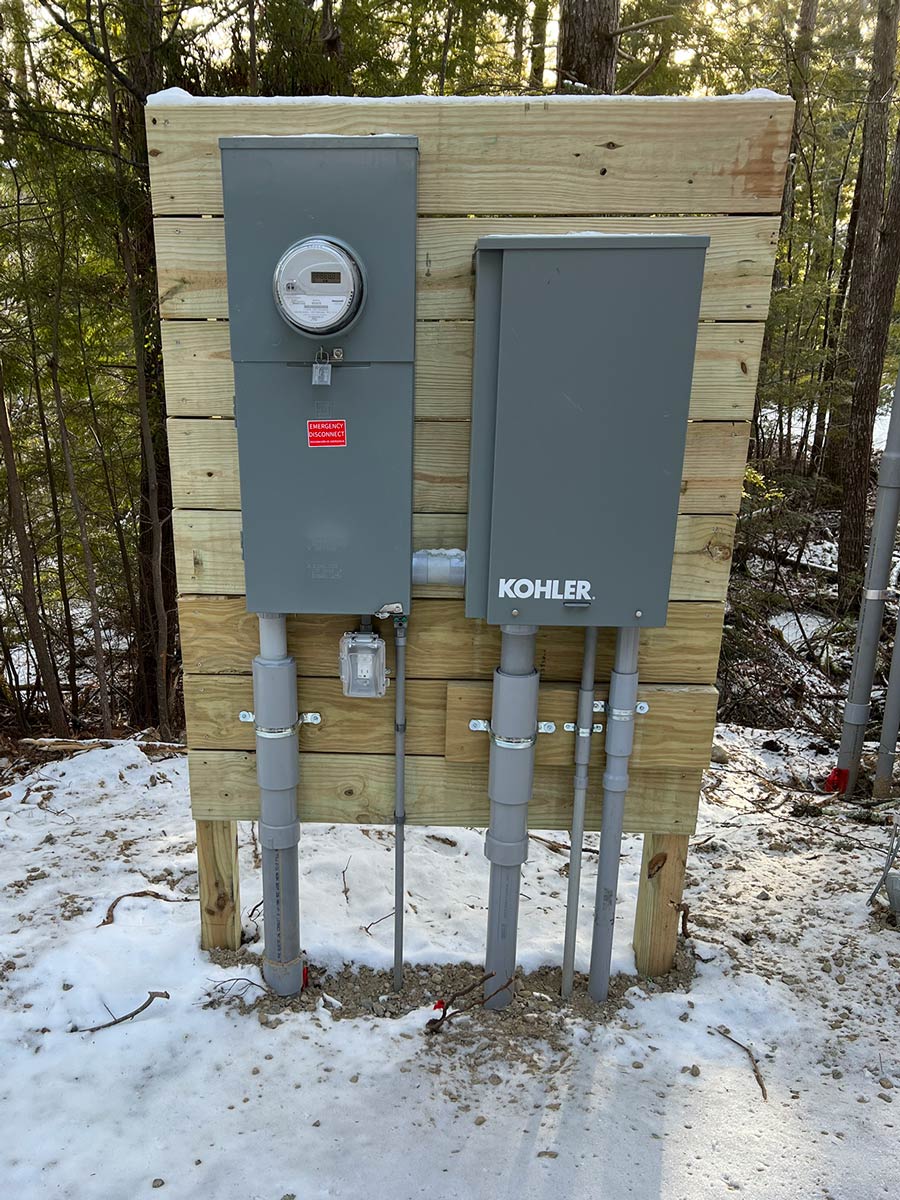 Utility meter, emergency disconnect, and KOHLER transfer switch on a plywood service board at a new-construction site